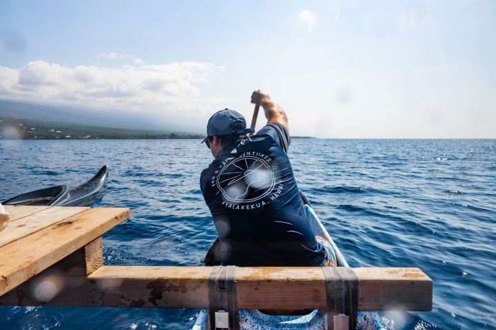 a person sitting on top of a wooden boat in a body of water